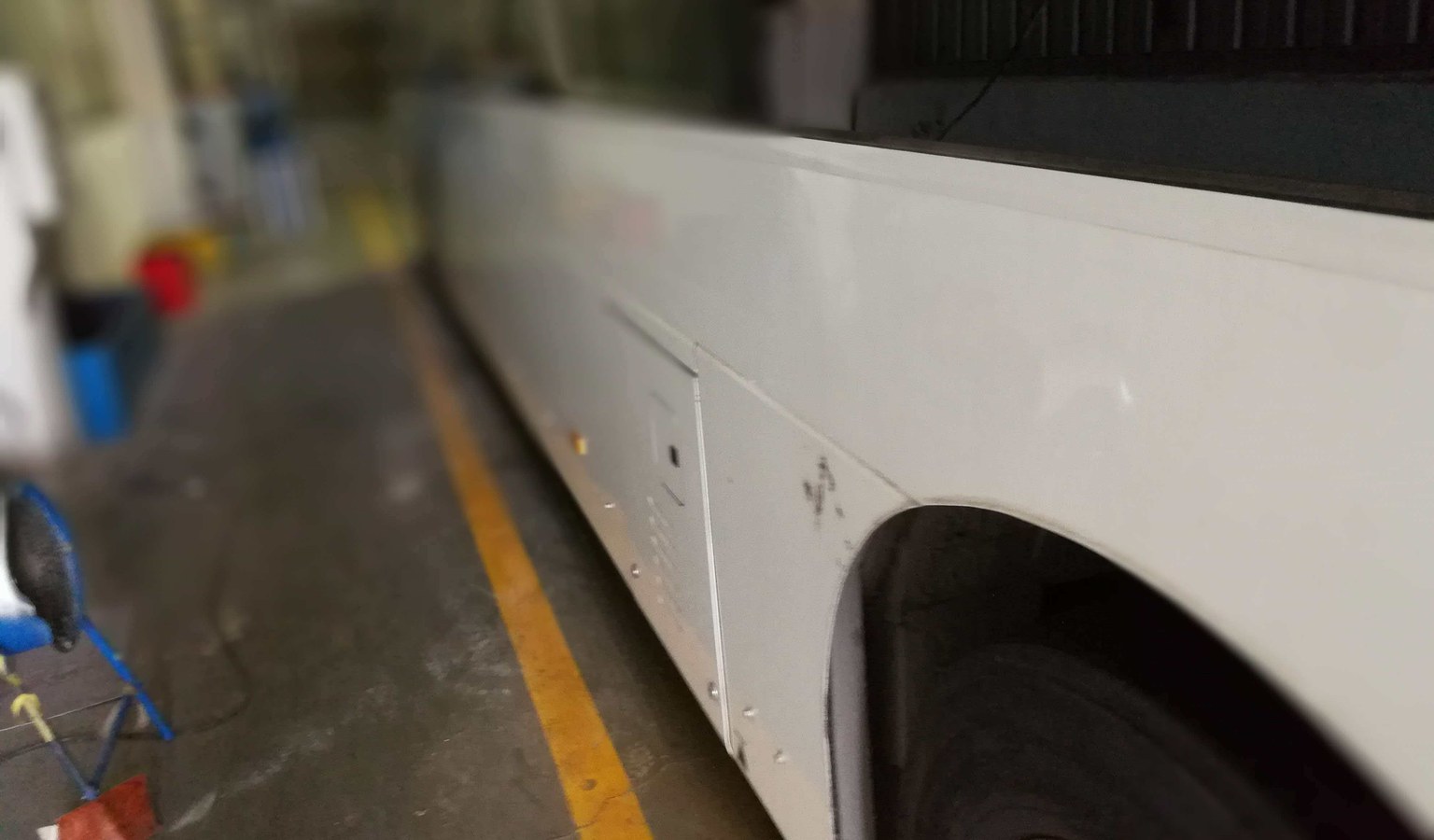 Bus composite side panel in a workshop during paint and surface quality inspection.